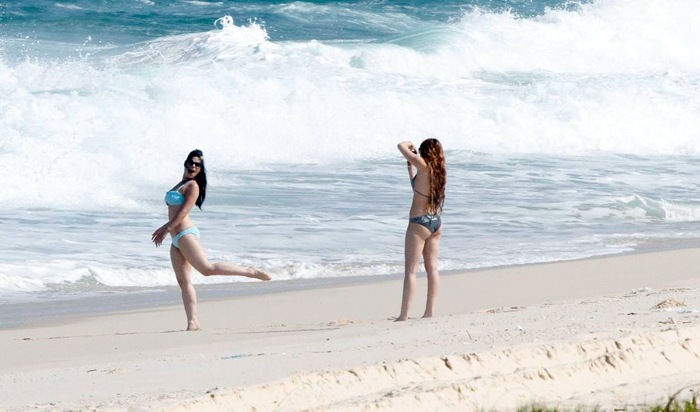 Miley e a amiga se divertem na praia fazendo as fotos