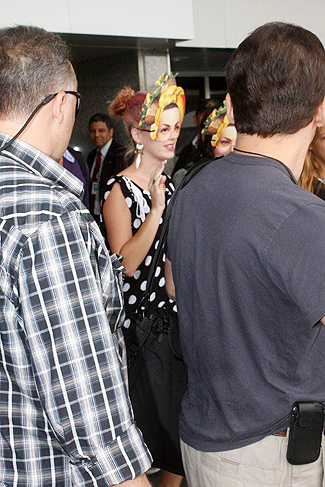 Cercada por seguranças, Katy Perry acena para fãs no aeroporto.