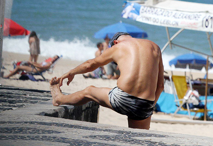 Marcos Caruso toma sol e faz alongamento na praia