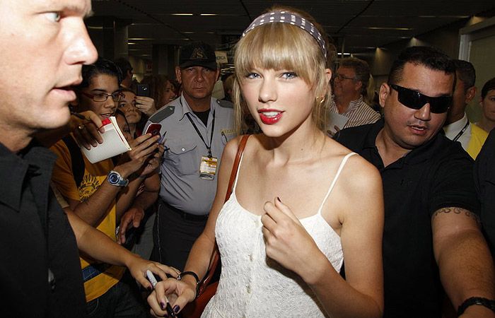 Taylor Swift distribui autógrafos em sua chegada ao Brasil
