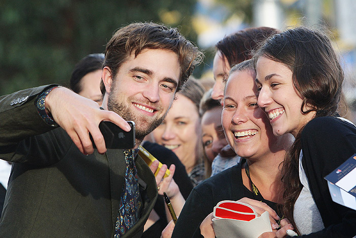 Robert Pattinson posa ao lado de fãs, na Austrália