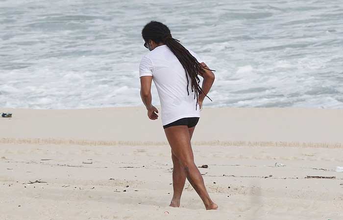 Falcão, do O Rappa, dança na praia de camiseta e sunga