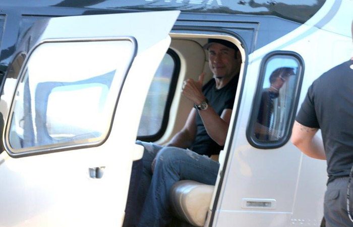 John Travolta mostra o bom humor ao embarcar em helicóptero no Rio