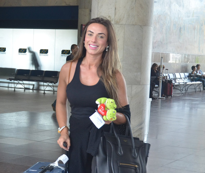 Nicole Bahls desembarca sorridente e ganha presente de fã no Rio de Janeiro