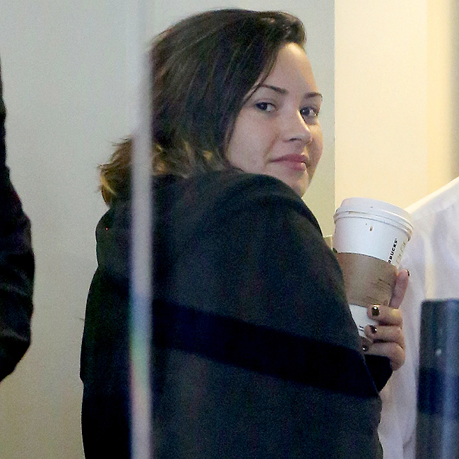 Demi Lovato viaja sem maquiagem e sorri para paparazzo em aeroporto