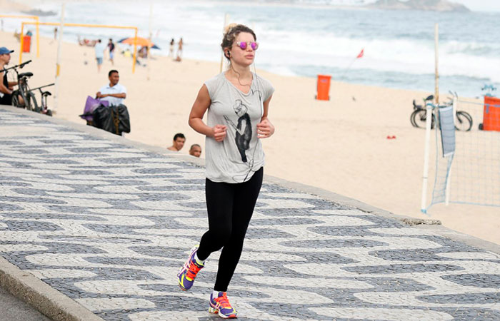 Com celular na mão, Bruna Linzmeyer corre na orla da praia