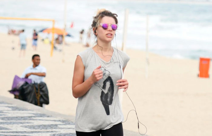 Com celular na mão, Bruna Linzmeyer corre na orla da praia
