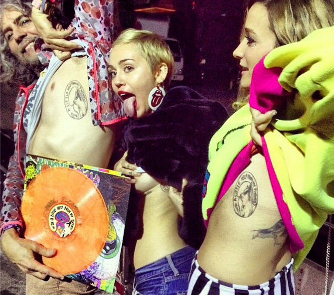 Miley Cyrus quase mostra os seios ao posar com amigos