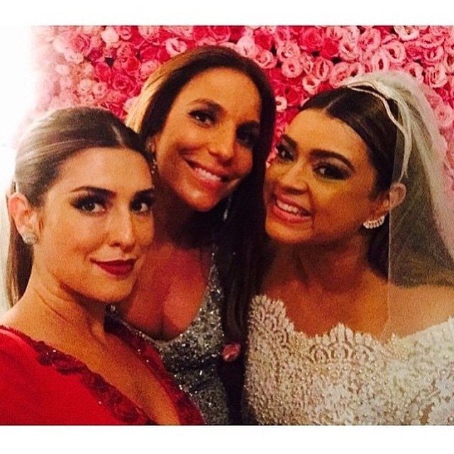 Fernanda Paes Leme e Ivete Sangalo, que foram madrinhas, posaram para uma selfie com a noiva. Olha o detalhe das pérolas do vestido da cantora. No fundo, o painel de rosas foi feito para os convidados fazerem as fotos