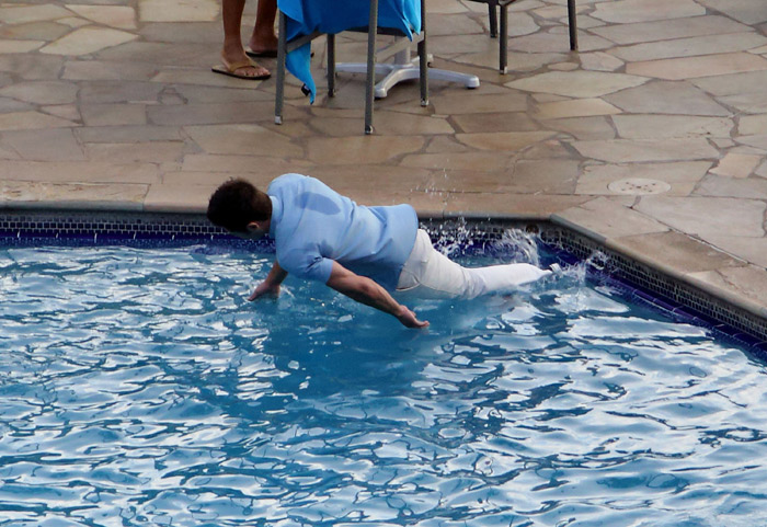 Zac Efron cai na piscina de roupa em filmagem no Havaí