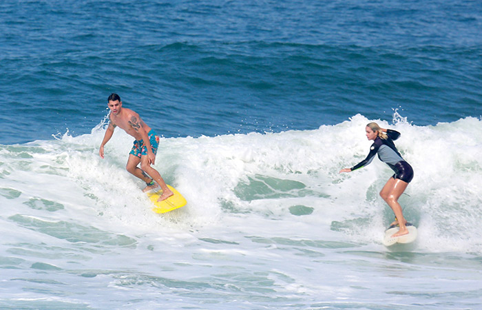 Juliano Cazarré mostra o corpão ao surfar com a esposa