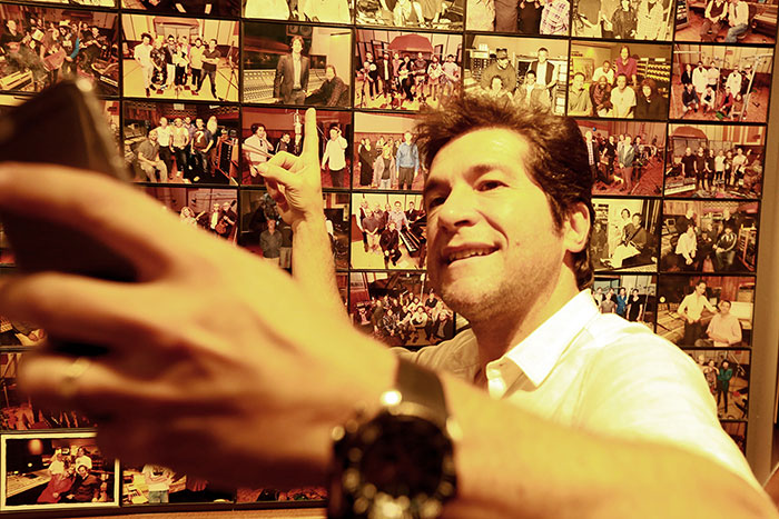 Daniel faz selfie em frente ao painel de fotos do estúdio