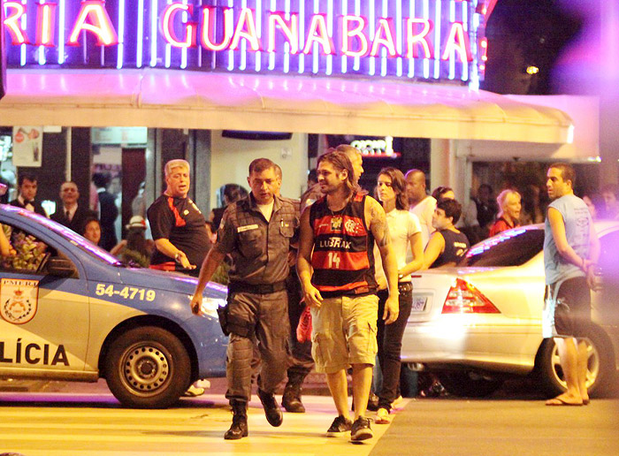 Sem se deixar abalar, o ator deixa o local enquanto conversa com um policial