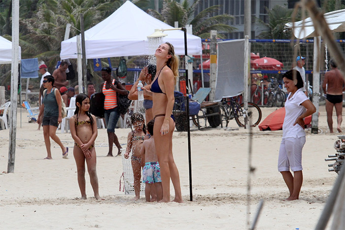 Acompanhada do filho, Letícia Birkheuer brinca na praia com mangueira