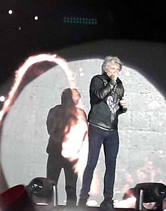 Jon Bon Jovi no cantinho do palco, perto da galera