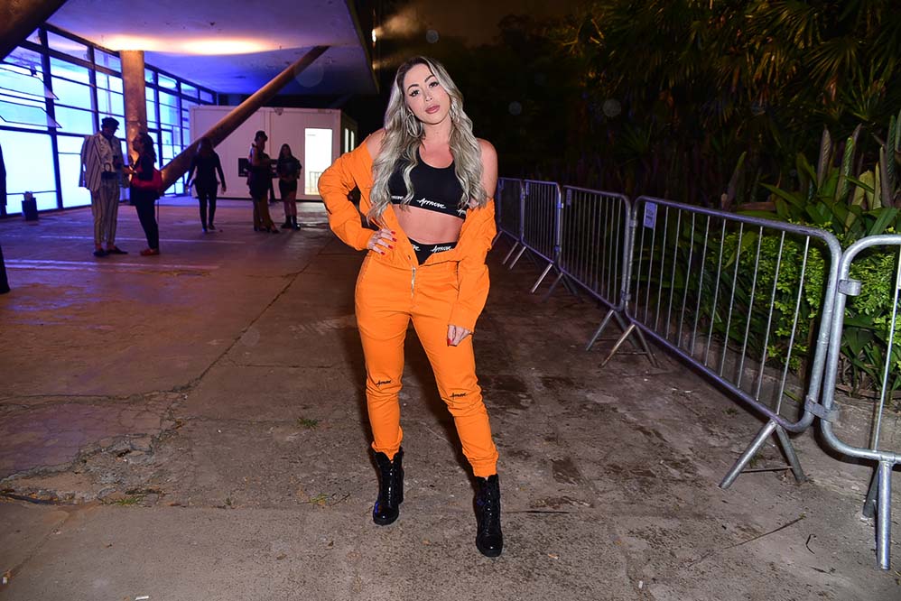 Ousada, Carol Narizinho escolheu um macacão laranja com a barriga de fora para o evento de moda