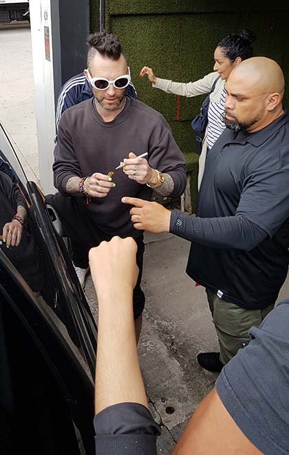 Adam Levine autografa CDs de fãs ao deixar cafeteria em São Paulo