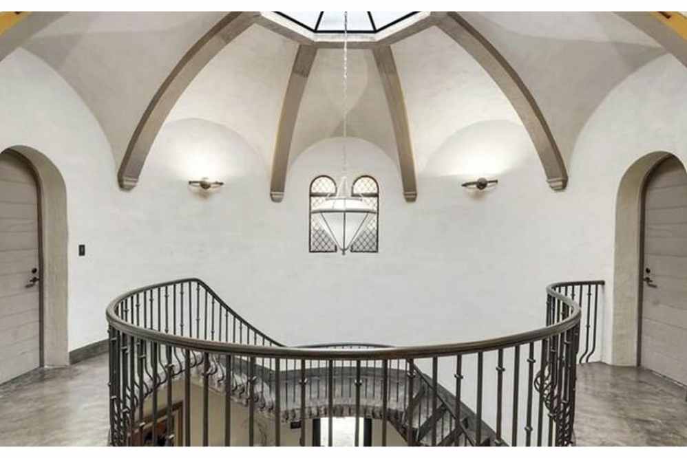 No interior da mansão uma escada em espiral leva ao saguão