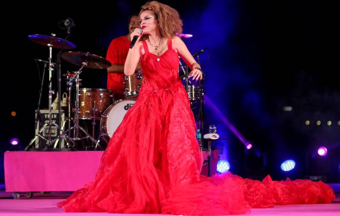 Vanessa da Mata se apresentando com um vestido vermelho volumoso
