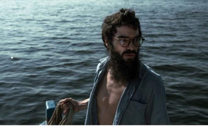 Caio Blat barbudo, num veleiro