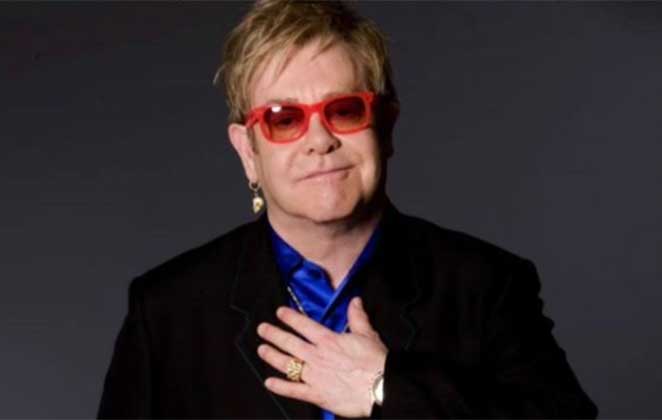 Elton John com a mão no peito