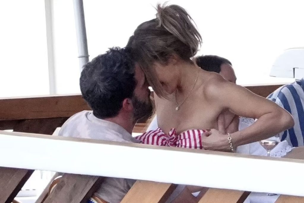 J.Lo ajeita o top vermelho e branco, alvo predileto da mão boba de seu namorado