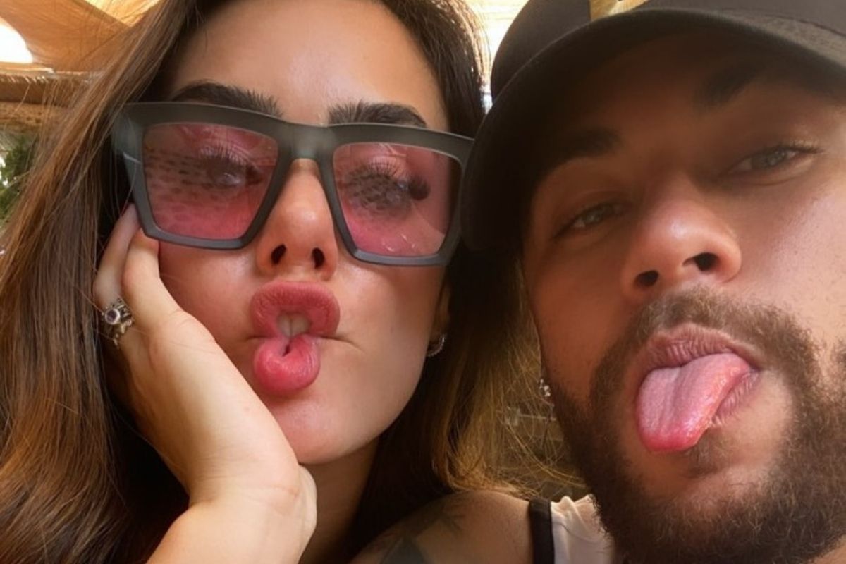 Selfie de Bruna Biancardi fazendo biquinho e usando óculos de sol ao lado de Neymar Jr. usando boné e mostrando a língua