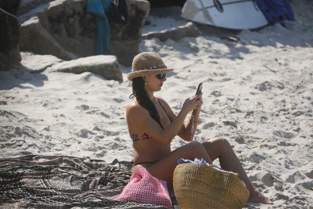 Isis Valverde usando celular na praia