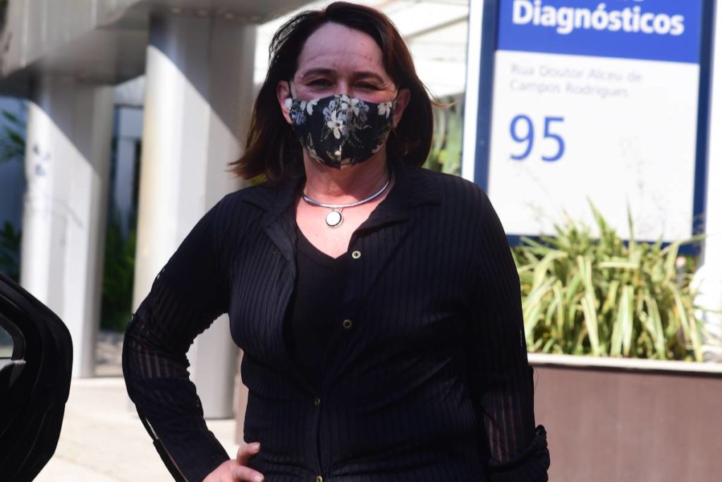 myrian rios saindo de hospital com roupa preta e máscara após receber alta de cirurgia na cabeça