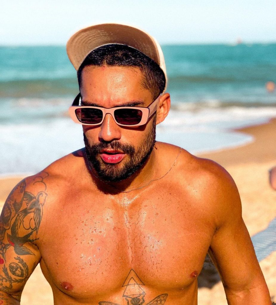 Bil Araujo de bone e oculos escuros na praia