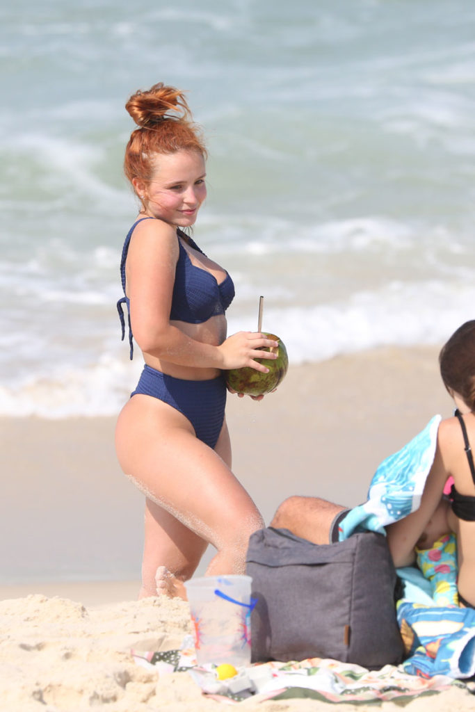 Larissa Manoela, tomando água de coco, posa para foto tirada por amiga na Praia da Barra da Tijuca