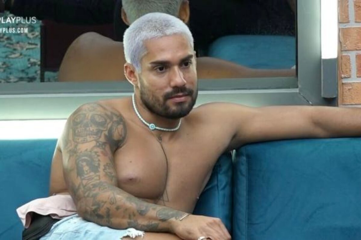 Bil Araújo sentado no sofá, de cabelo descolorido, sem camisa