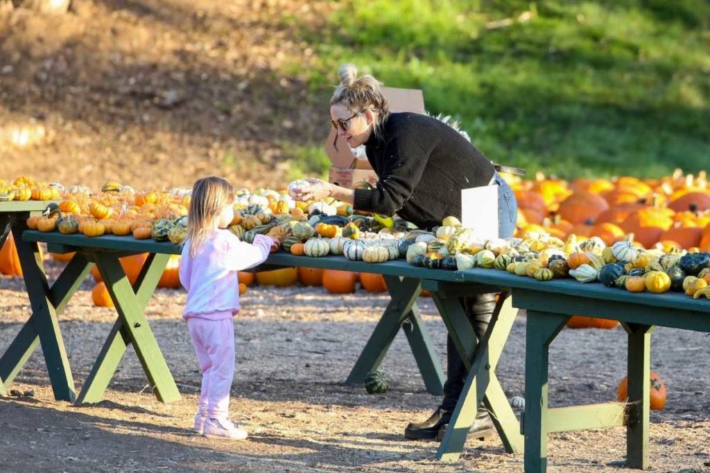 kate hudson mostrando abóbora para a filha em plantação