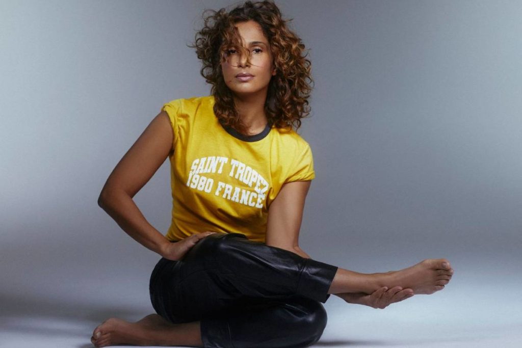 camila pitanga posando com pernas uma em cima da outra em fundo neutro