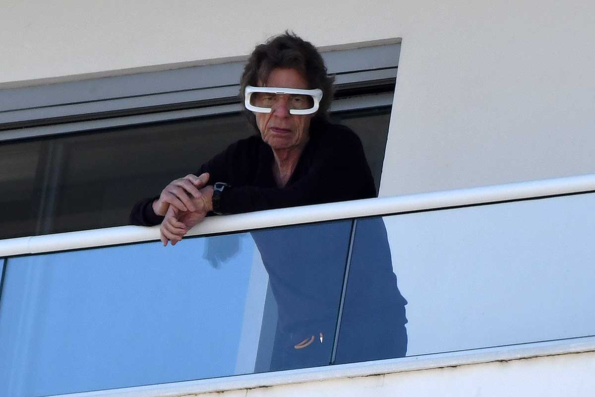 Mick Jagger com óculos terapêutico na varanda de hotel