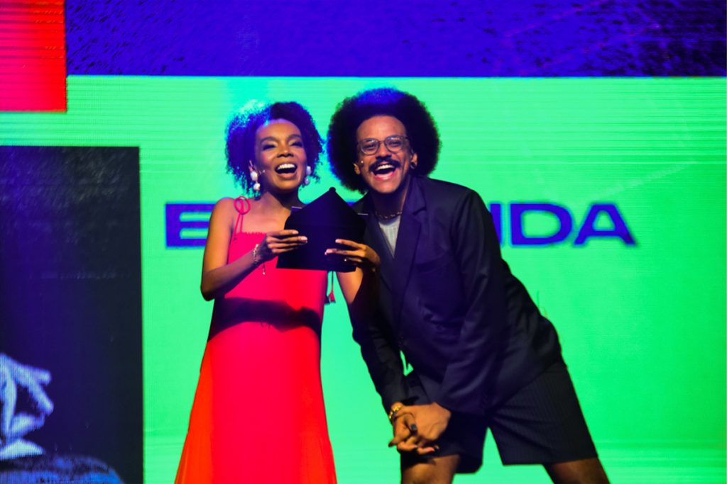 Thelma e João Luiz em palco de premiação.