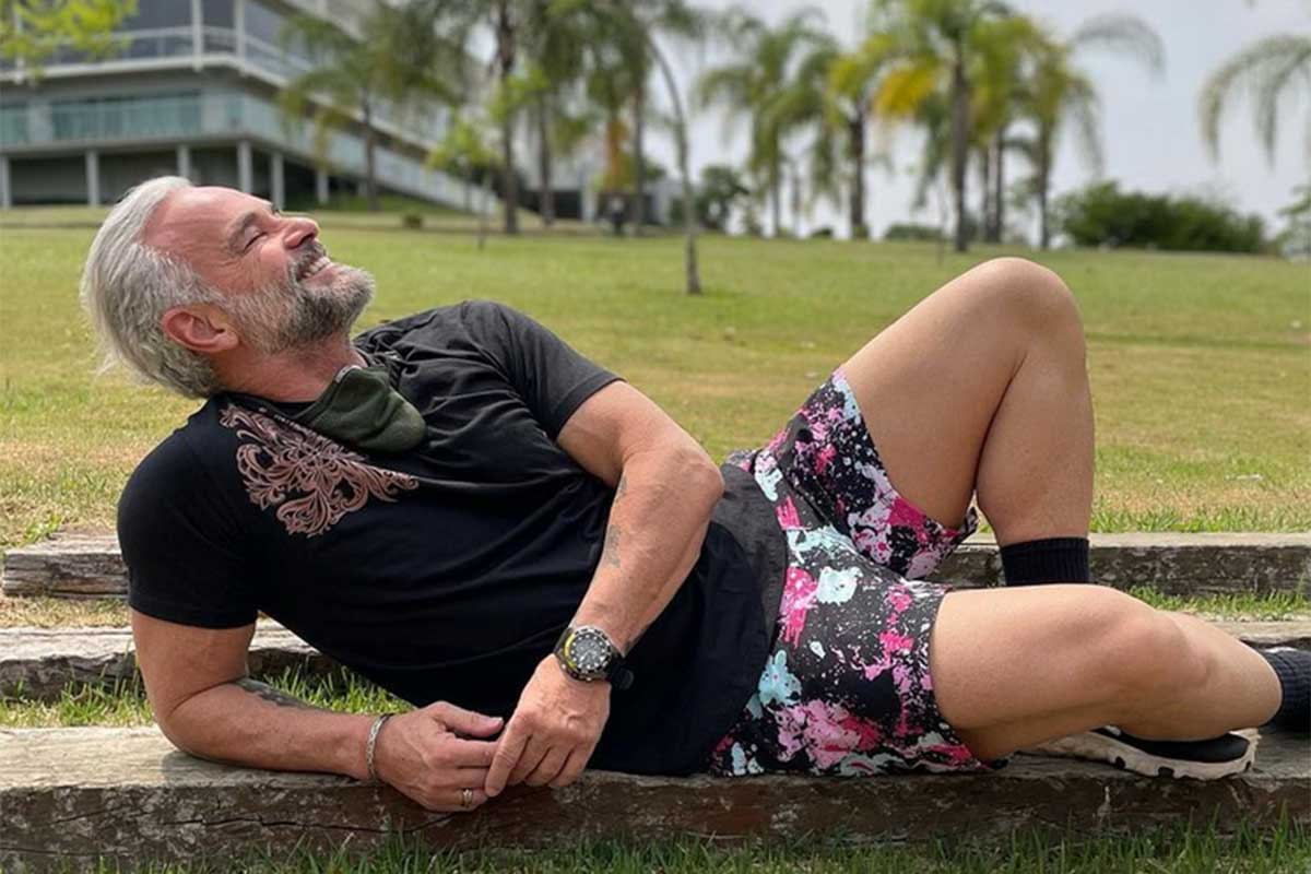Mateus Carrieri deitado na grama, de camiseta e shorts