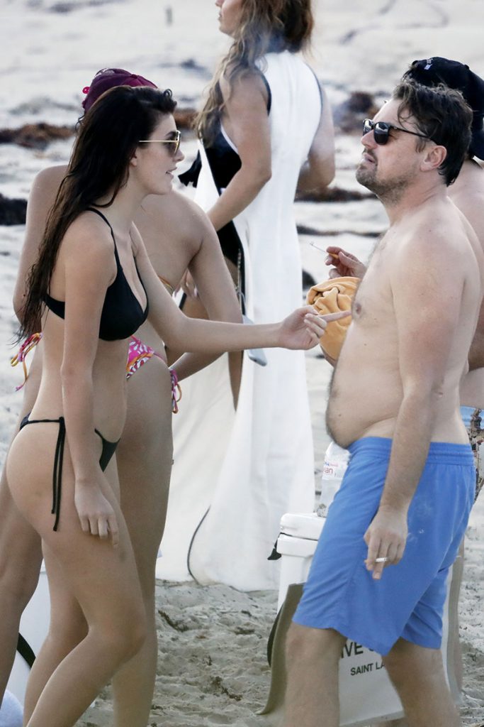 Camila Morrone conversa com DiCaprio, que segura um cigarro e exibe barriga saliente