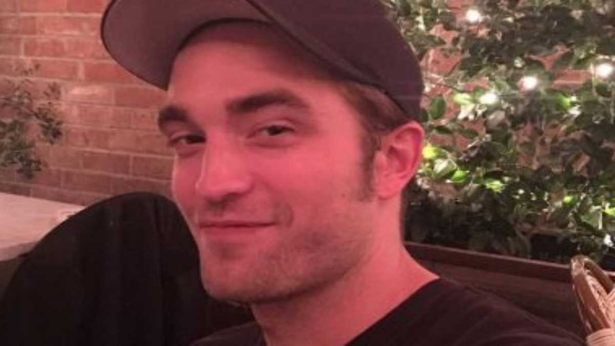 Robert Pattinson sorrindo de boné