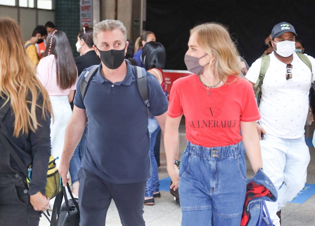 Luciano Huck e Angélica de mãos dadas em aeroporto