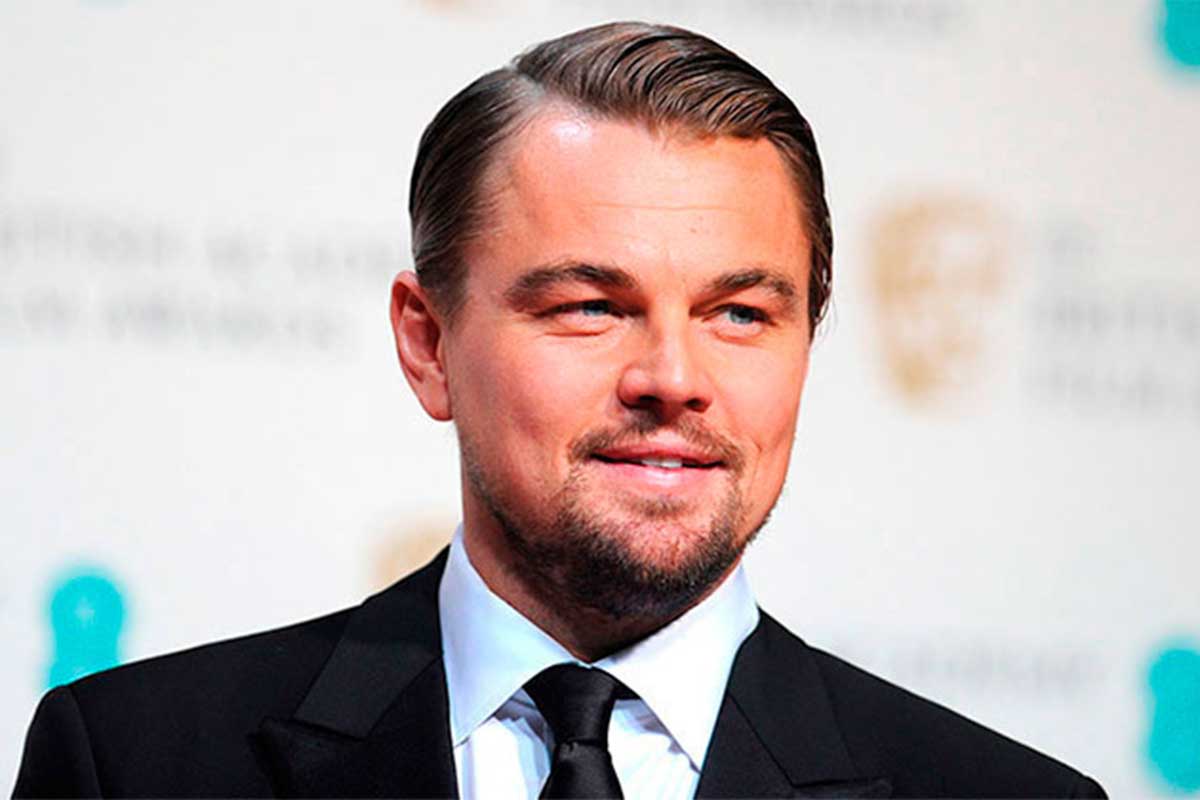 Leonardo DiCaprio sorridente, de paletó e gravata