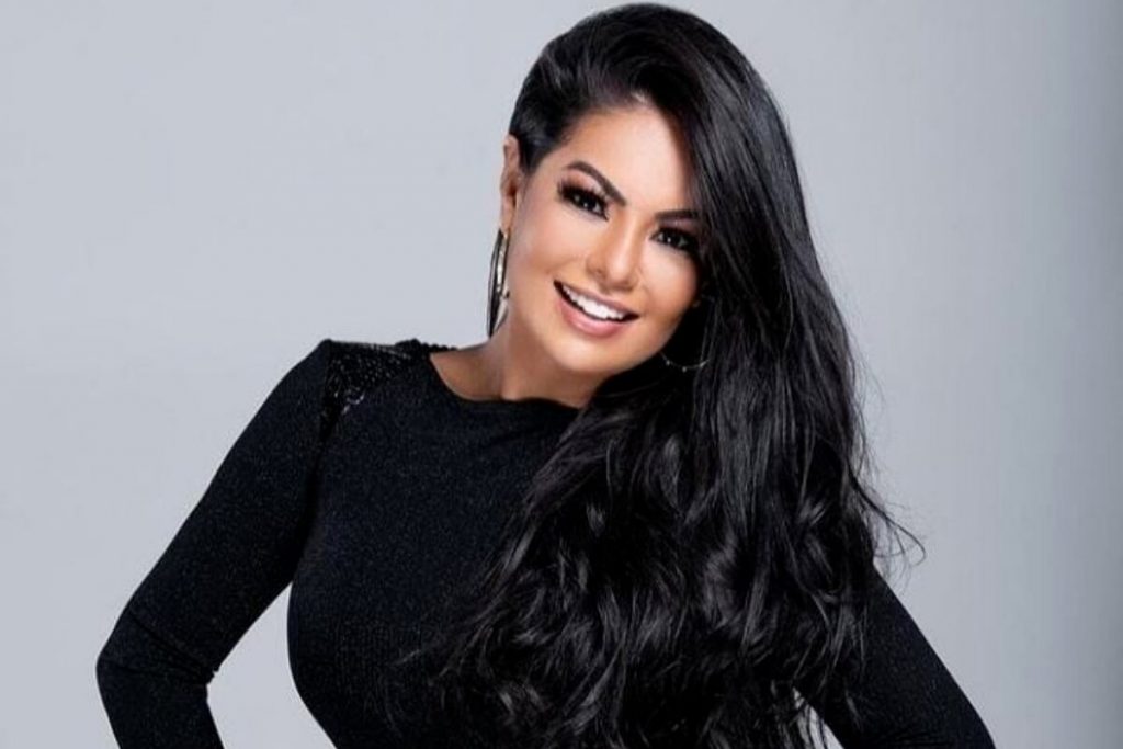 Paulinha Abelha sorrindo, de roupa preta