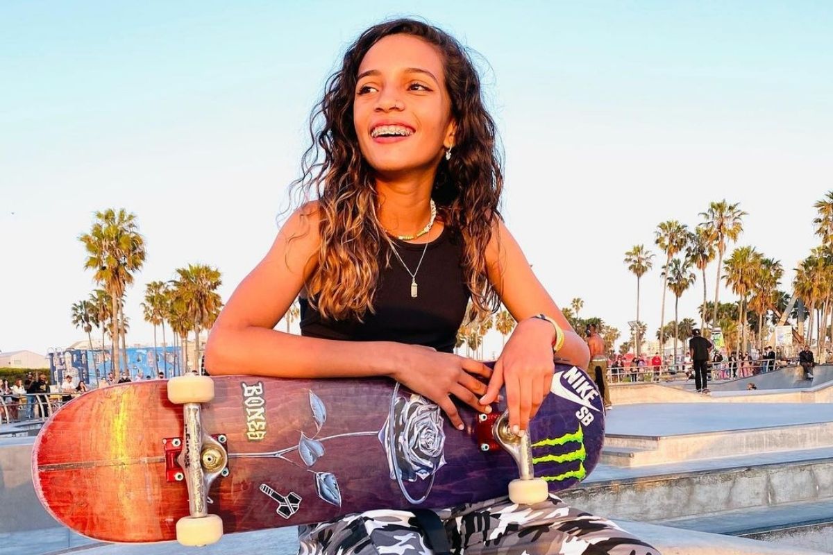 Rayssa Leal em foto sorrindo, sentada com um skate no colo