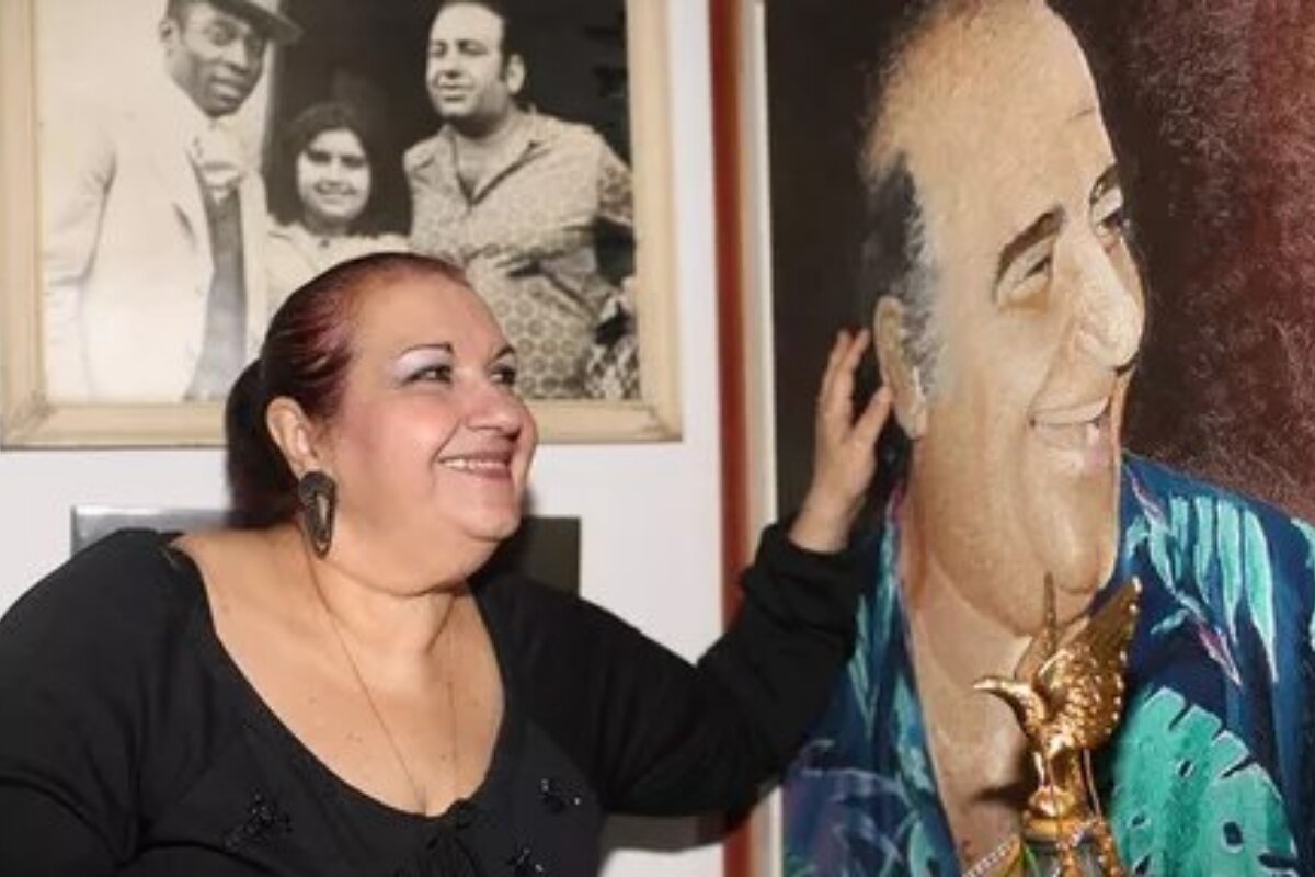 Vitória Cury aponta para uma foto do pai, o falecido Bolinha