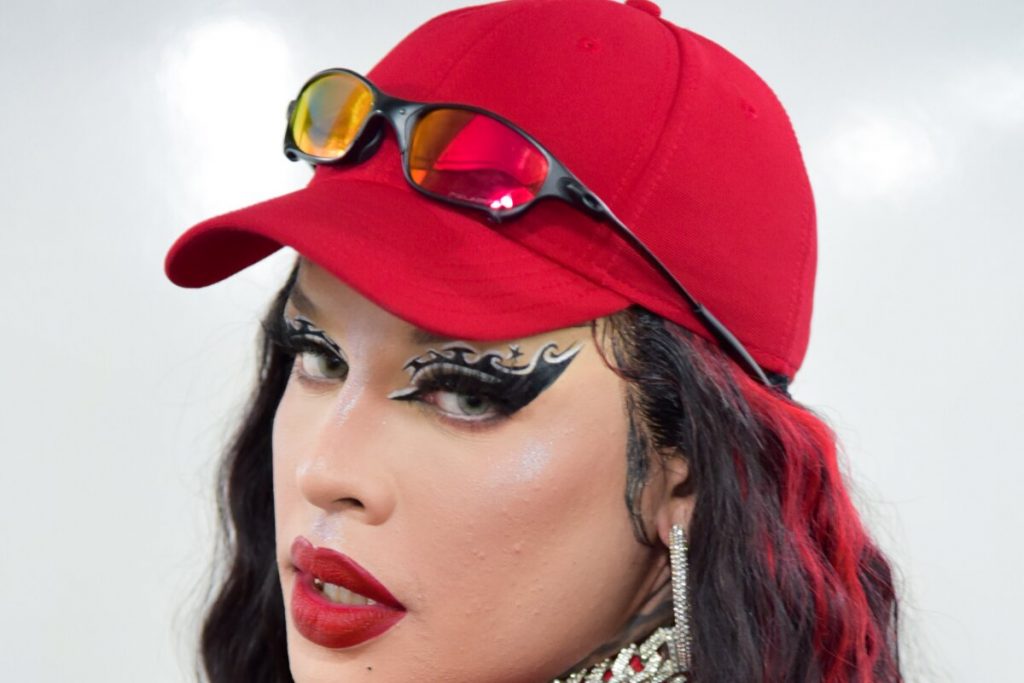 Gloria Groove de boné vermelho e maquiagem marcante