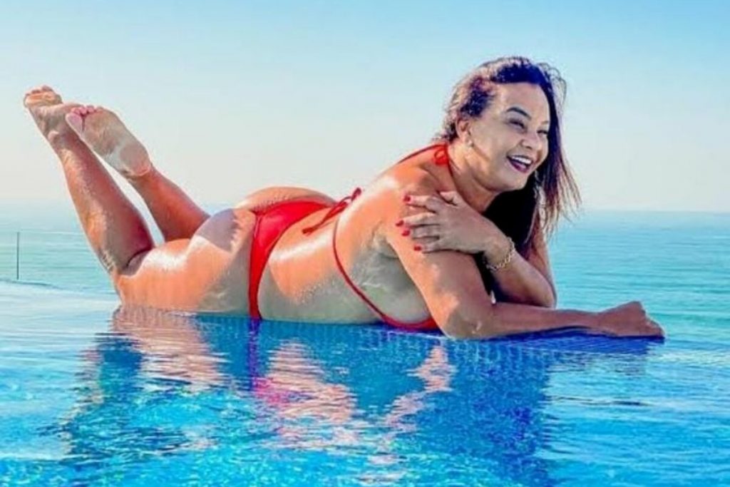 Solange Couto deitada na borda da piscina, de biquini vermelho
