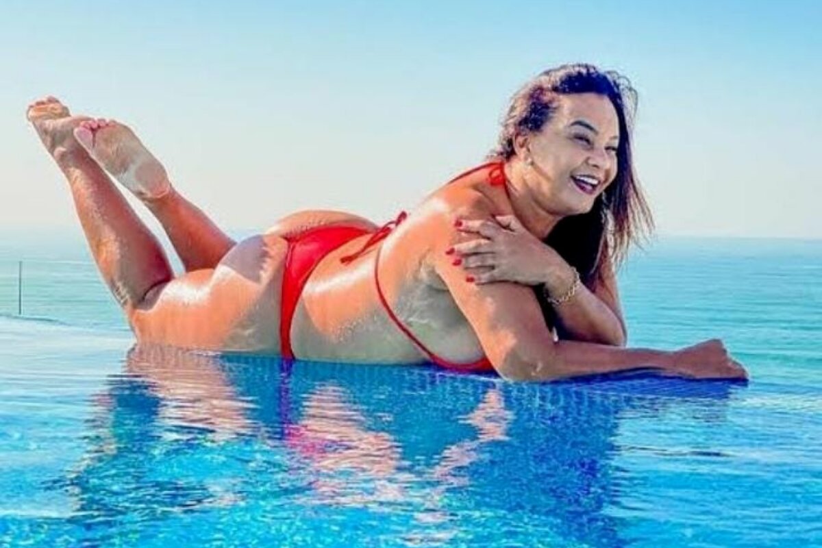 Solange Couto deitada na borda da piscina, de biquini vermelho