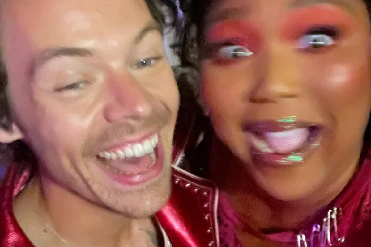 harry styles e lizzo posando sorridentes com a câmera desfocada