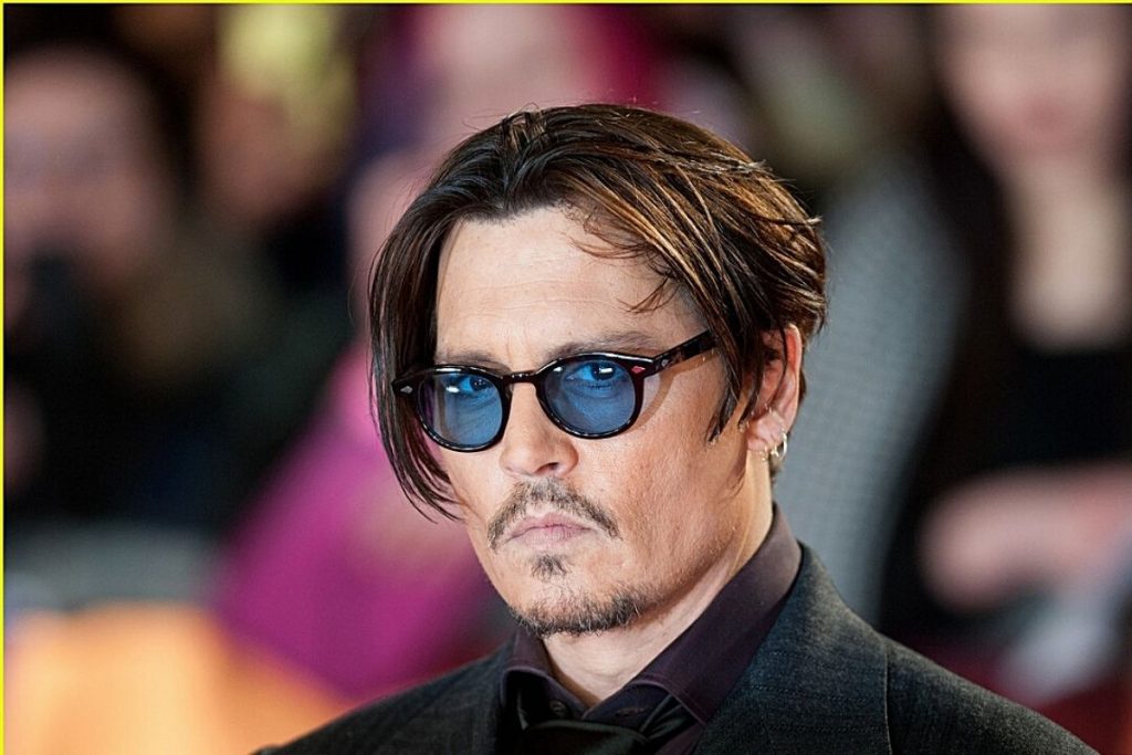 johnny depp posando com óculos de lente azul e terno