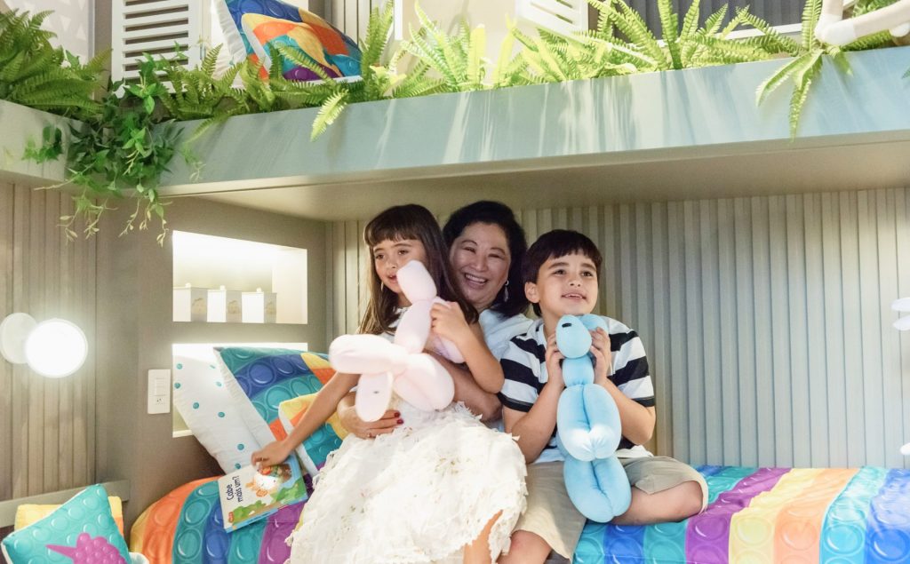 Kika Sato e netos posando para foto em quarto infantil